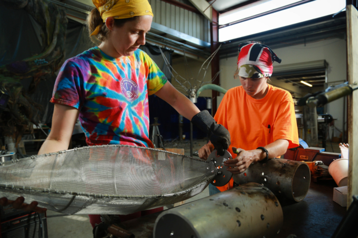 Two ThemeWorks employees working with machinery.